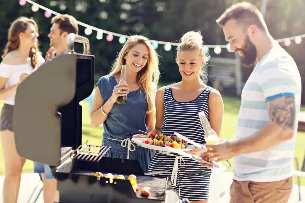 a group of people standing around a barbecue grill